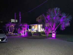 Ein Wohnhaus mit gut beleuchteter Auffahrt, einem sichtbaren Carport und einer Terrasse mit Überdachung.
