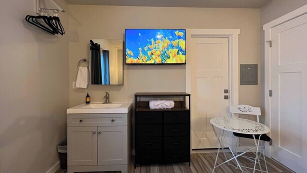 A bathroom with a sink, mirror, and a flat-screen TV mounted above it. - Hike & Chill, Walk to Coffee Restaurants Bar (Mossyrock)