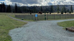 A gravel path leading to a fenced area with a wooden structure in the background. - Hike & Chill, Walk to Coffee Restaurants Bar (Mossyrock)