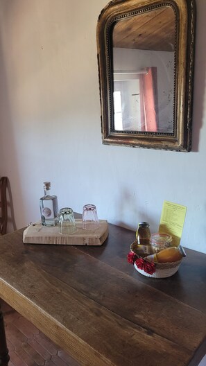 A wooden table with a mirror, a tray, a bottle, a jar, and a bowl with flowers.