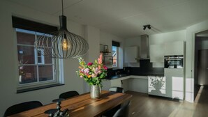 Ett modernt kök med en matplats, en hängande lampa och en vas med blommor.