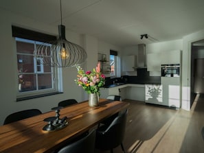 Eine moderne Küche mit Essbereich, einer Pendelleuchte und einer Vase mit Blumen.
