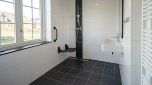 Ett badrum med ett fönster, en dusch och ett handfat.
