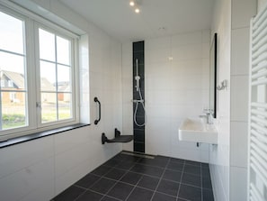 Ein Badezimmer mit Fenster, Dusche und Waschbecken.