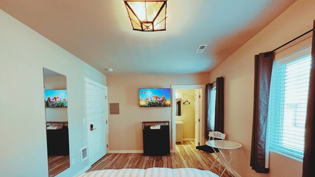 Un dormitorio con cama, escritorio, silla y ventana con cortinas.