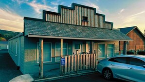 Un edificio con techo inclinado, cerca de madera y señal de estacionamiento para discapacitados.