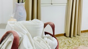 Une pièce avec une fenêtre, un vase contenant des plantes séchées et un panier rempli de serviettes.