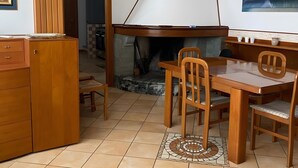 Un espace repas agrémenté d’une cheminée, de meubles en bois et d’un sol carrelé.
