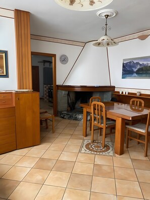 A dining area with a fireplace, wooden furniture, and a tiled floor.