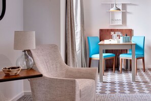 A room with a chair, a table, a lamp, a vase, and a patterned floor. - 1BR Suite w/ Kitchen & Sofa Bed | Daily Breakfast! (Liverpool)