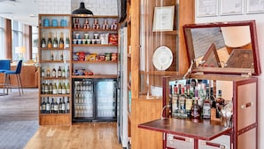 A bar area with shelves of bottles, a refrigerator, and a wooden counter with a mirror. - Accessible King Studio w/ Breakfast | Arena Nearby (Liverpool)
