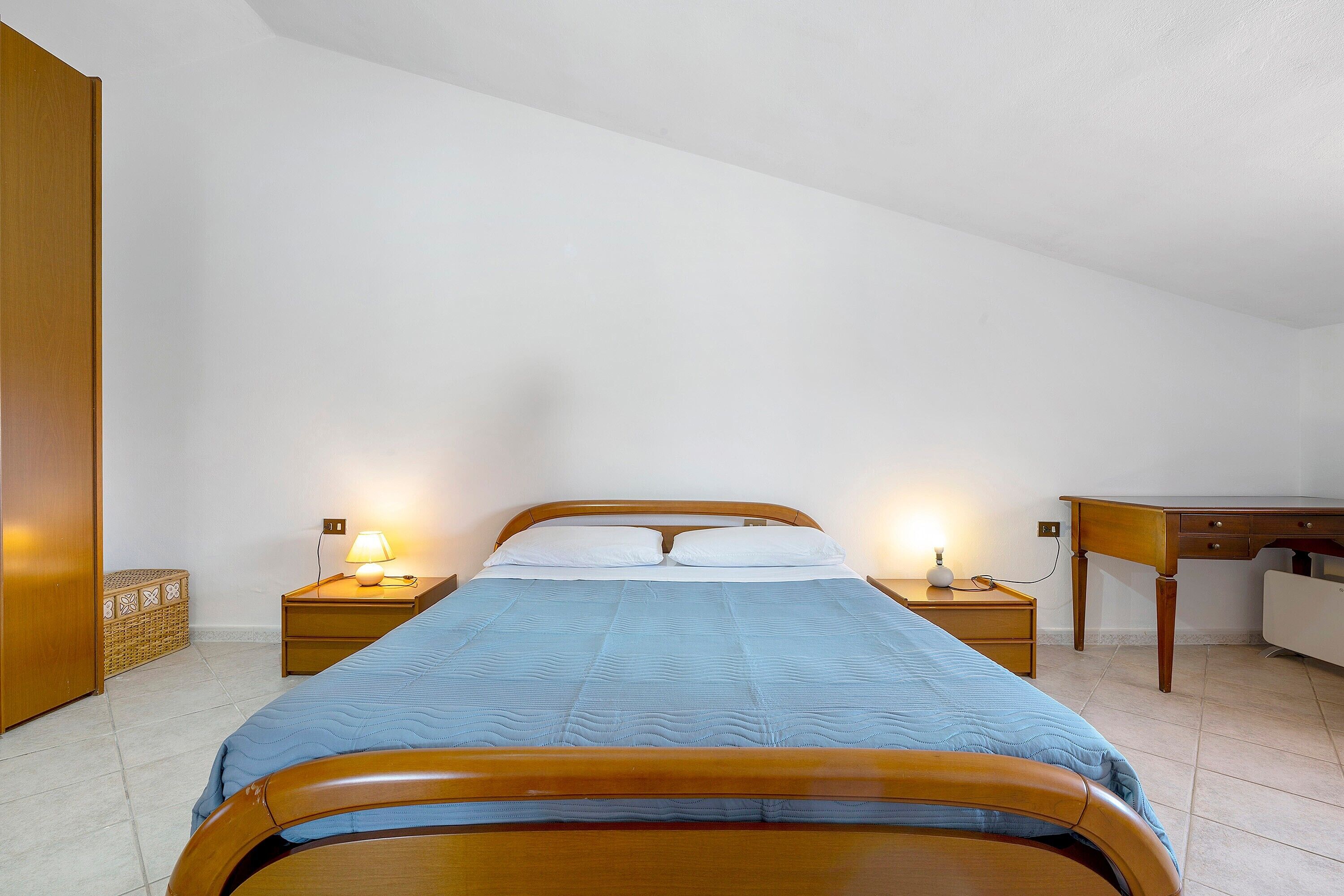 Ein Schlafzimmer mit einem Bett, zwei Nachttischen, einem Schreibtisch und einem Kleiderschrank.