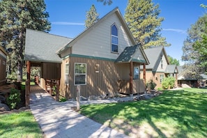 A two-story house with a covered porch, a stone pathway, and a well-maintained lawn.