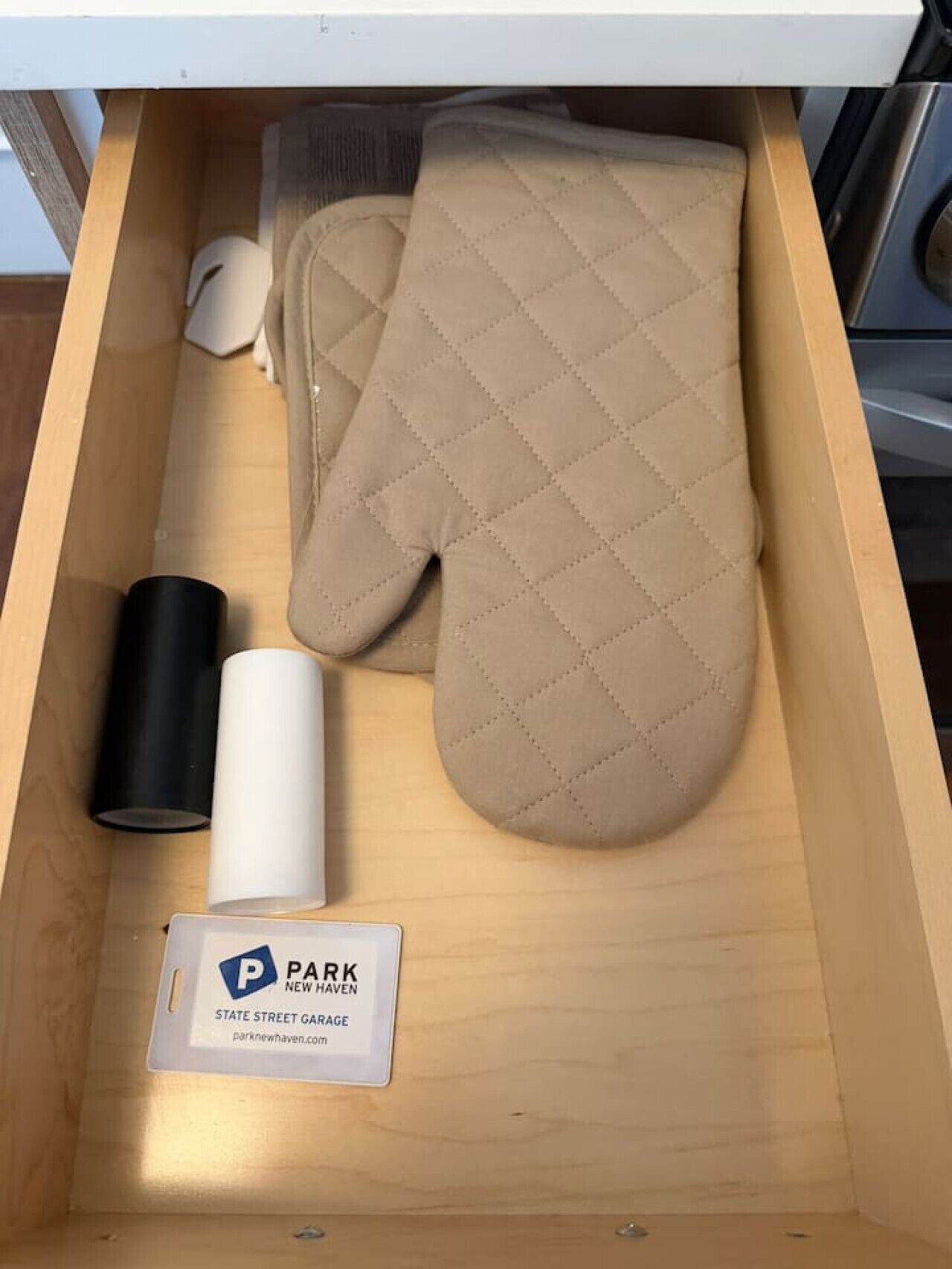A wooden drawer containing a quilted item, a cylindrical object, and a sign with text.