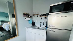 Et lille køkken med et køleskab, en vask og en mikrobølgeovn.