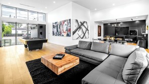A modern living room with a pool table, grey sofa, and artwork on the walls. - Noir Luxury Home, Design District w/ Pool, Billiard (Miami)