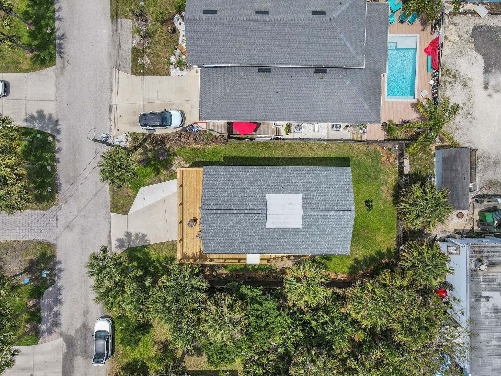 Une vue aérienne d’un quartier résidentiel, avec un grand immeuble à toit plat, une piscine et une allée où sont garées des voitures.