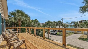 A wooden deck with chairs, a railing, and a view of a street with palm trees and a building. - Steps to Beach Walk to Pier, Restaurants & Nightlife Near Downtown & Amphitheatre (St. Augustine)