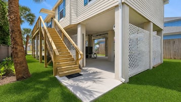 A two-story house with a wooden staircase, a covered porch, and a fenced backyard.