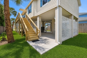 Ein zweistöckiges Haus mit einer Holztreppe, einer Veranda und einem umzäunten Garten.