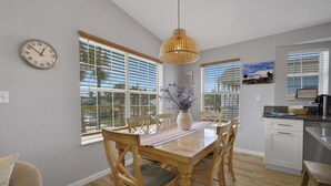 A dining area with a wooden table, chairs, a clock, and a hanging light fixture. - Steps to Beach Walk to Pier, Restaurants & Nightlife Near Downtown & Amphitheatre (St. Augustine)