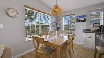 A dining area with a wooden table, chairs, a clock, and a hanging light fixture.