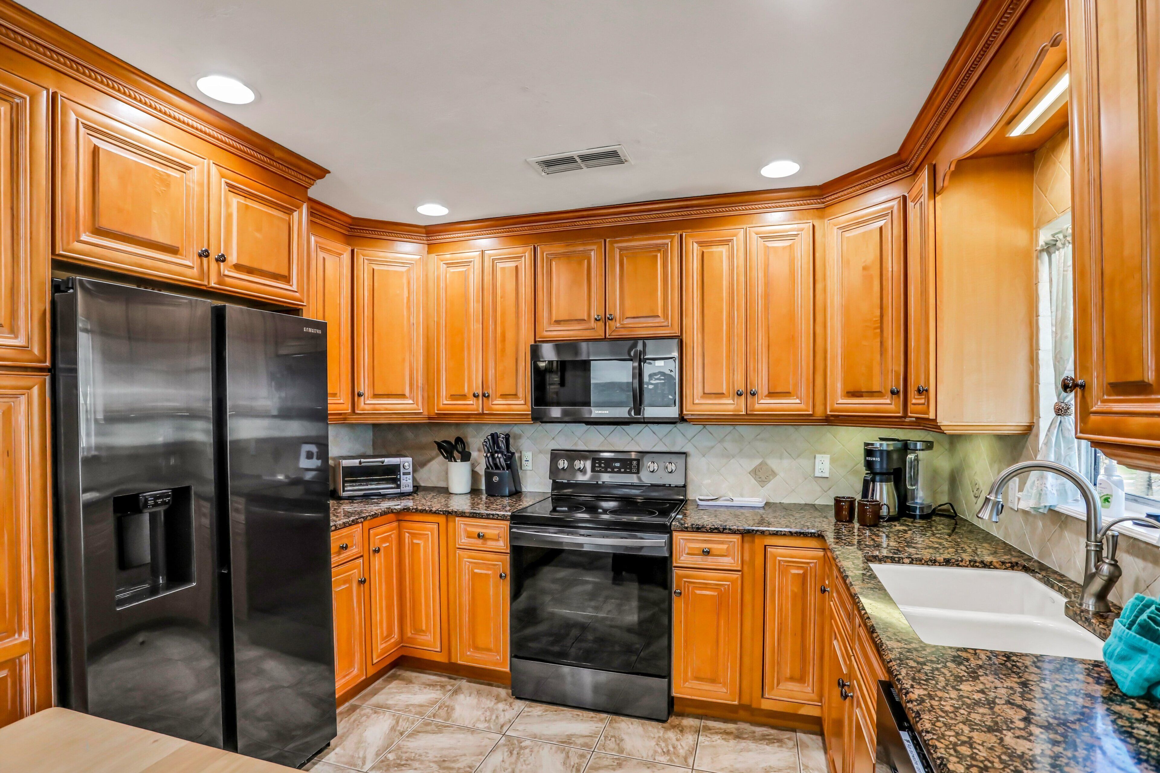 A kitchen with wooden cabinets, stainless steel appliances, granite countertops, and a built-in microwave.