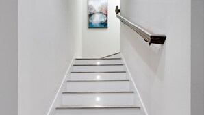 A staircase with white walls, a handrail, and a painting on the wall. - Pet-friendly 4BR Beach Home Walk to Beach & Jacksonville Beach Pier Fenced Yard (Jacksonville Beach)