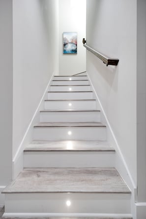 Eine Treppe mit weißen Wänden, einer Handläufung und einem Gemälde an der Wand.