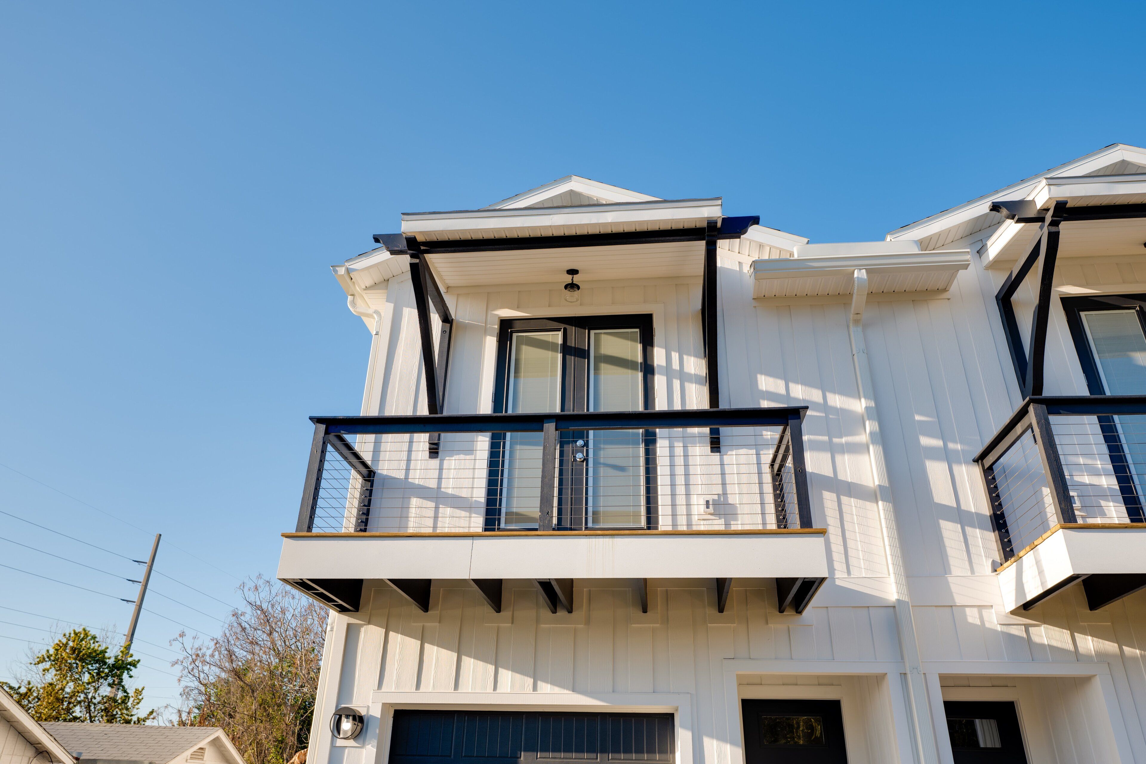 A multi-story building with a balcony, large windows, and a garage.