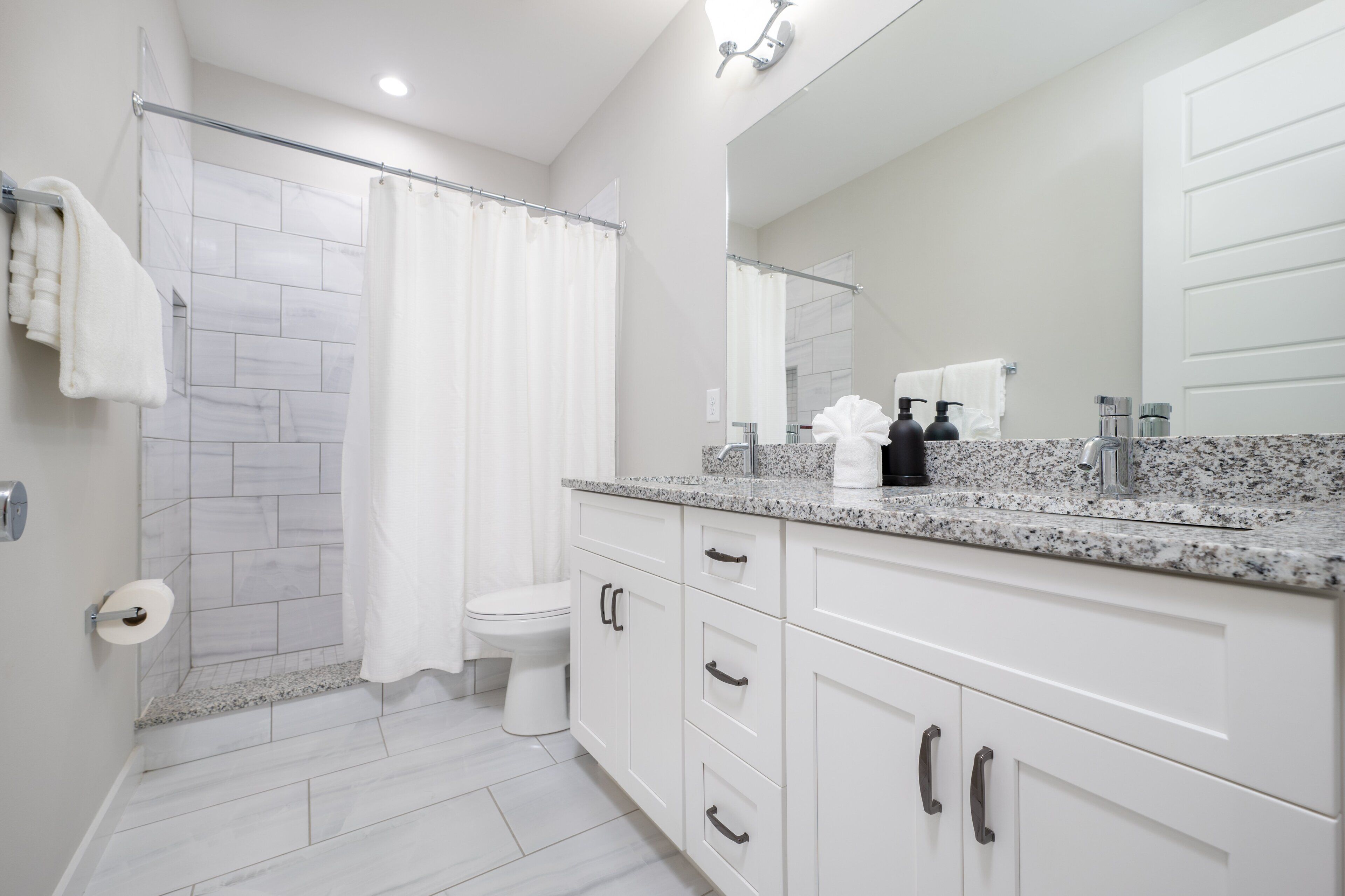 A modern bathroom with a shower, toilet, and vanity with a mirror.
