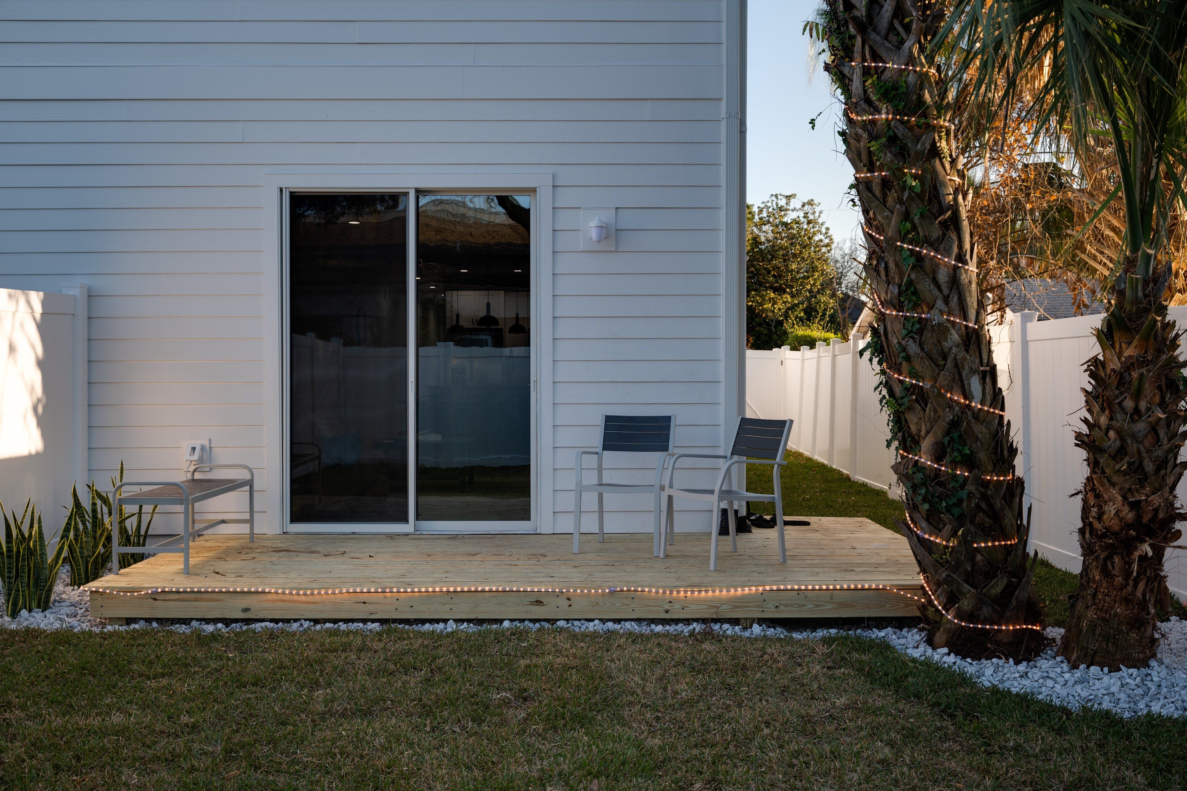 Una casa con un portico coperto, una porta scorrevole in vetro e un recinto bianco.