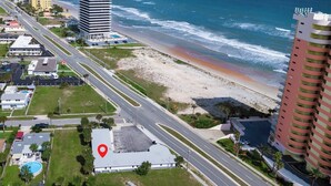 Vista aerea di una zona costiera con spiaggia, strada e edifici.
