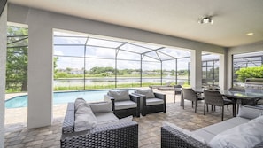 Ein überdachter Außenbereich mit Pool, Korbmöbeln und Grill.