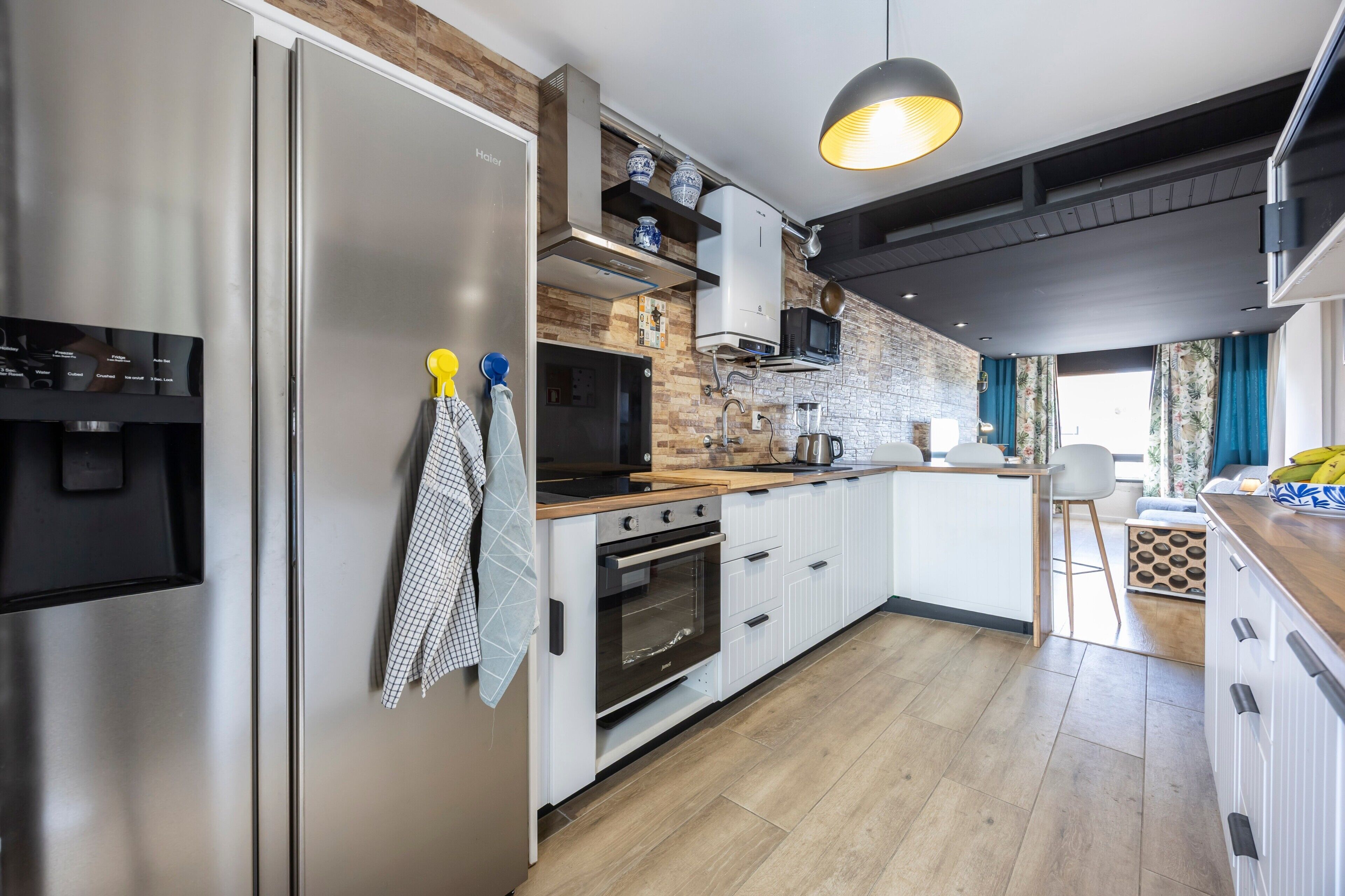 A modern kitchen with a stainless steel refrigerator, a built-in oven, a microwave, and a wooden countertop.