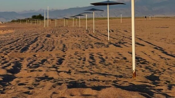 A desert landscape with multiple white poles and dark umbrellas, suggesting a beach or outdoor area. - 45 Inn (Tosor)
