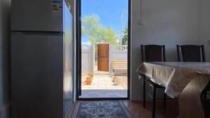 A kitchen with a refrigerator, a dining table with chairs, a patterned rug, and a door leading to an outdoor area. - 45 Inn (Tosor)