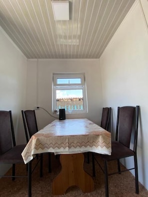 A dining area with a table and chairs, a window with a view, and a ceiling light fixture.