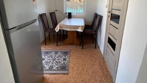 A compact kitchen with a refrigerator, dining table, chairs, and a window. - 45 Inn (Tosor)