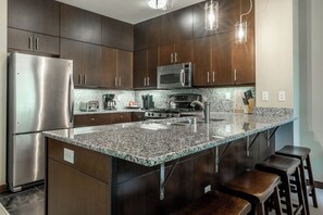 Eine moderne Küche mit Edelstahlgeräten, Granit Arbeitsplatten und dunklen Holzausziehtüren.