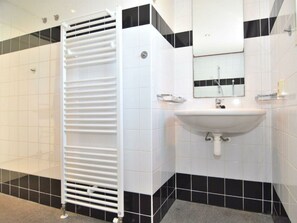 Ein Badezimmer mit einem weißen Waschbecken, einem Spiegel und einem Handtuchhalter.