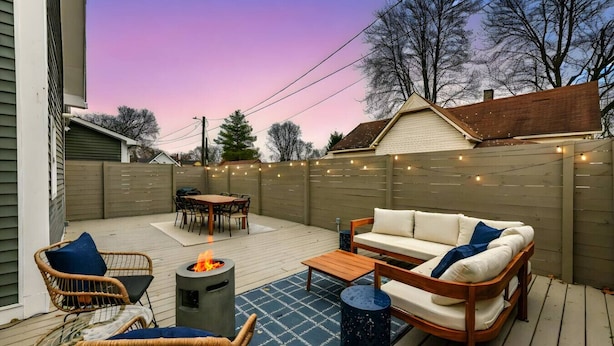 A backyard patio with a fire pit, outdoor furniture, and string lights.