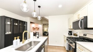 A modern kitchen with a central island, stainless steel appliances, and pendant lighting.