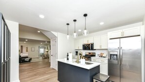A modern kitchen with white cabinets, stainless steel appliances, and a central island.