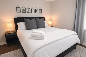 A neatly made bed with white linens and gray pillows, two bedside lamps, and framed botanical prints on the wall. - 4BD 2BA Ranch on Catherine Westfield Fenced Yard (Westfield)
