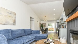 Un salon moderne avec un canapé d’angle, une table basse en bois et une cheminée.