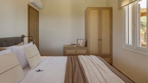 Une chambre à coucher avec un lit, des oreillers, une table de chevet, une armoire et une fenêtre.