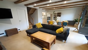 A modern living room with a sectional sofa, wooden coffee table, and a staircase leading to an upper level.