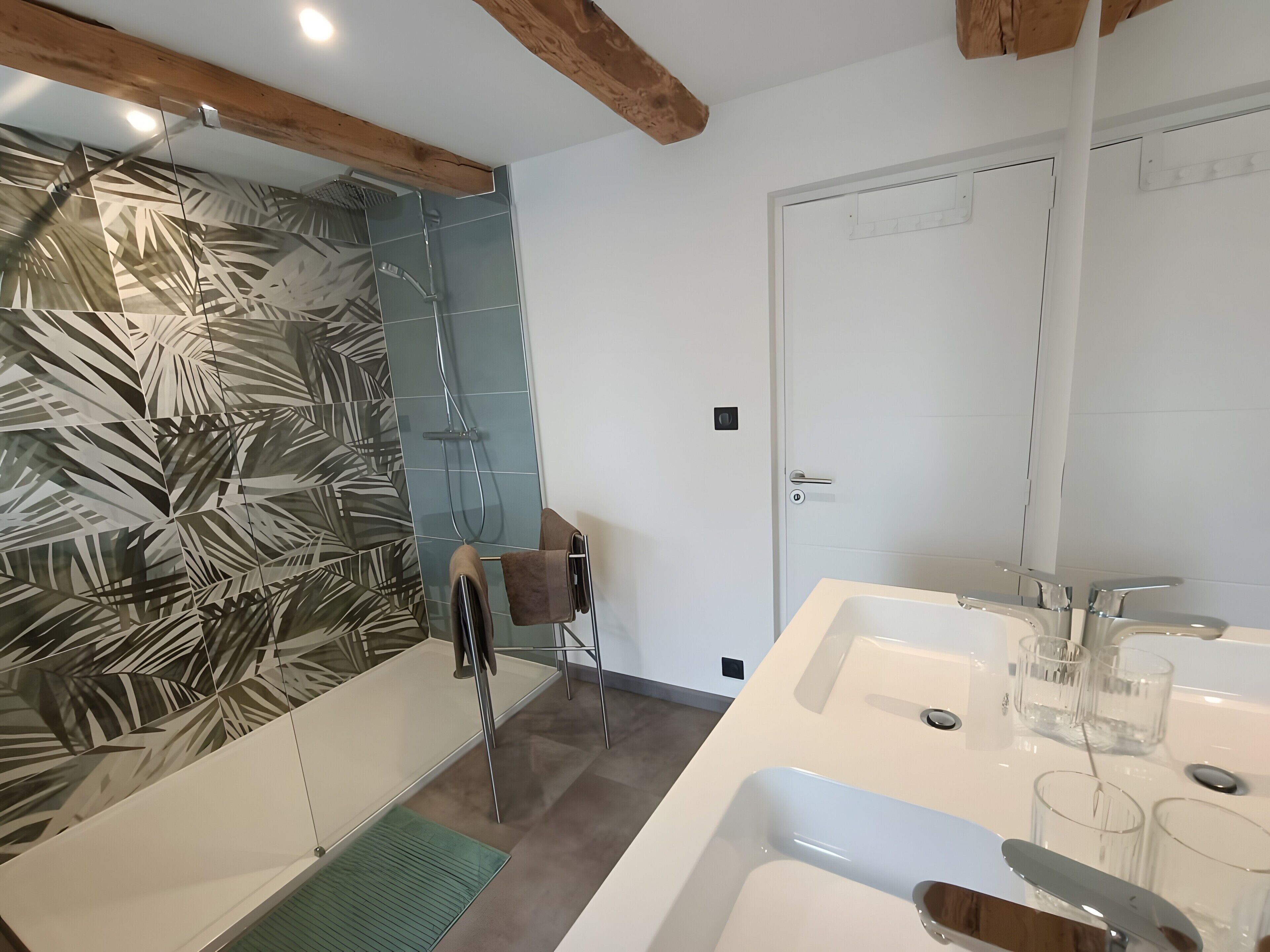 Une salle de bain moderne avec une douche, un lavabo et un miroir.