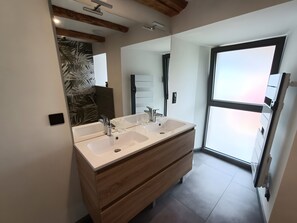 A modern bathroom with a double sink vanity, wooden drawers, a large mirror, and a view through a glass door. - Holiday Home “Gîte 9 Personnes Puy Mary” with Mountain View, Private Terrace & Garden (Le Claux)